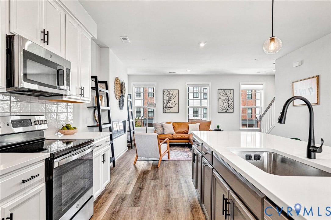 Kitchen featuring stainless steel appliances, white cabinetry, and wood-finish flooring
