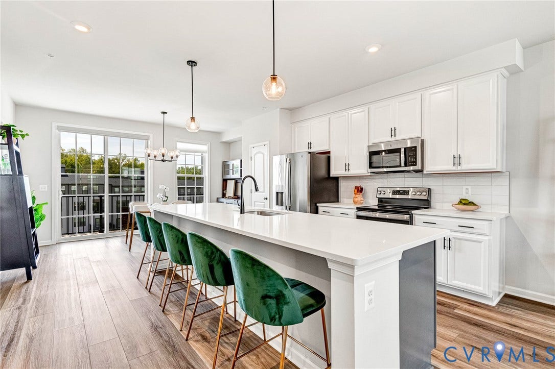 Kitchen featuring white cabinetry, stainless steel appliances, wood-finish flooring, a center island with a light-colored countertop, and a white subway tile backsplash