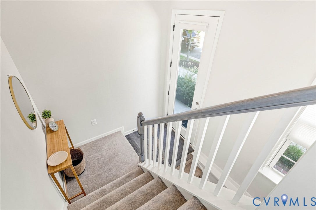Staircase featuring carpeted treads, painted risers, and a wooden handrail with white balusters