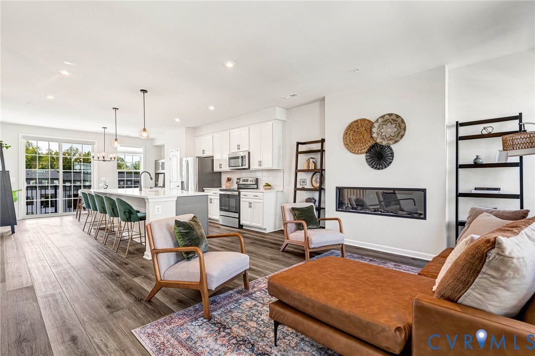 Open-concept living area featuring wood-finish flooring, a linear fireplace, and a kitchen with an island