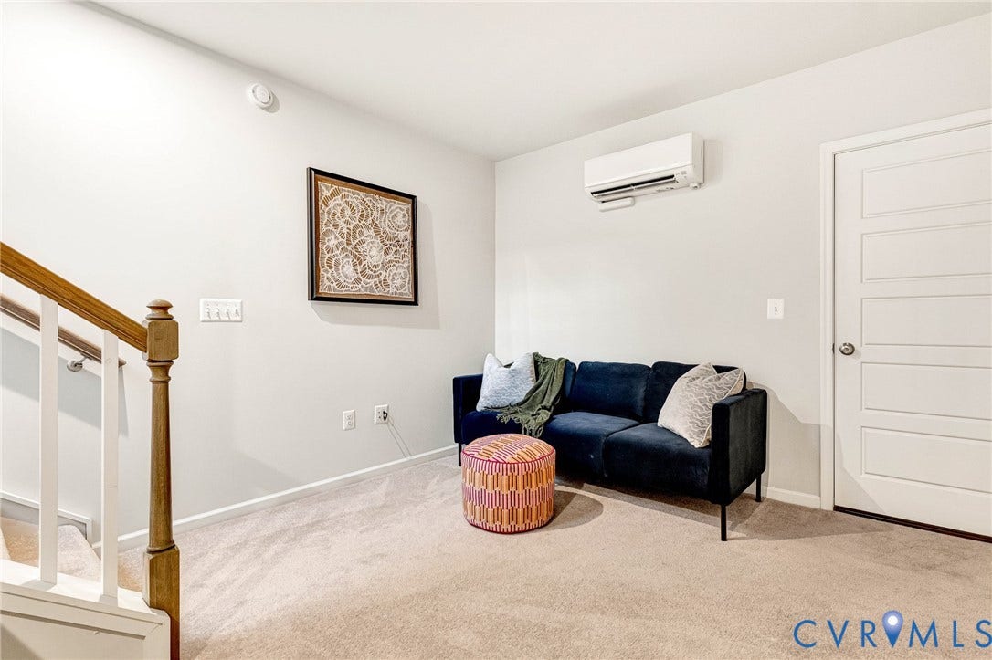 Carpeted flooring, white paneled interior door, and a wall-mounted mini-split HVAC unit
