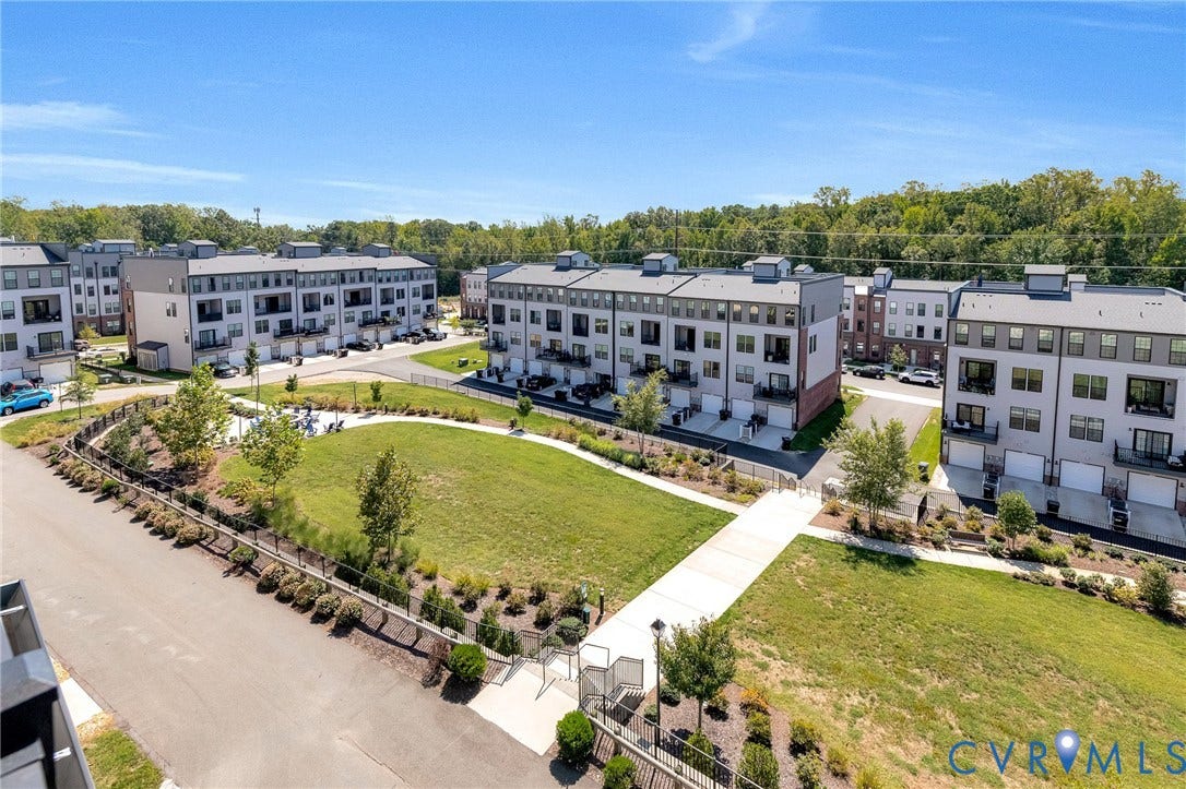 Modern townhomes with integrated garages, private balconies, and surrounding green spaces featuring paved walkways