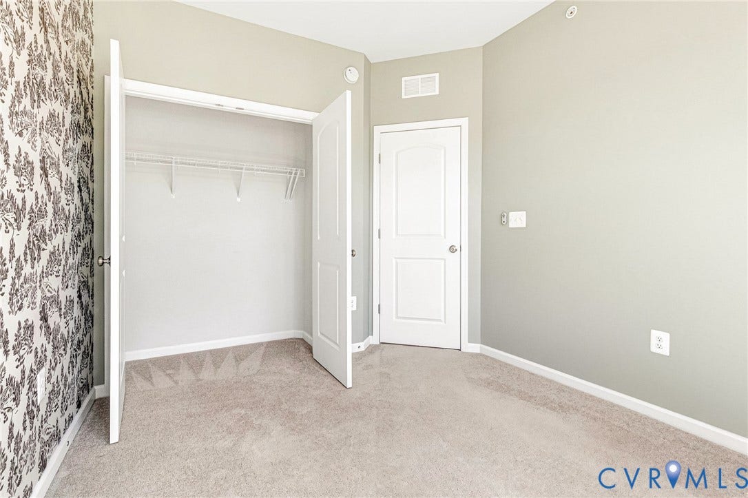 Plush carpet flooring, neutral paint tones, and a closet with wire shelving