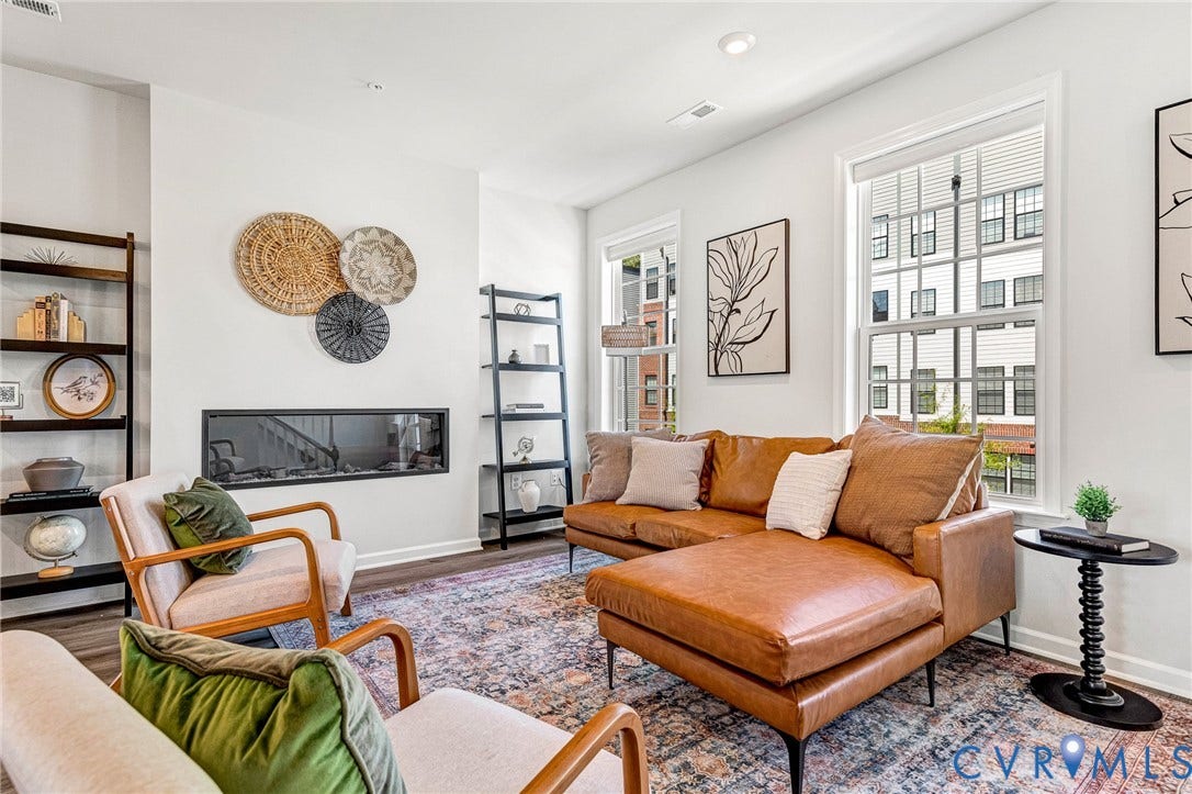 Recessed fireplace with a dark surround, wood-finish flooring, white walls, and multiple windows