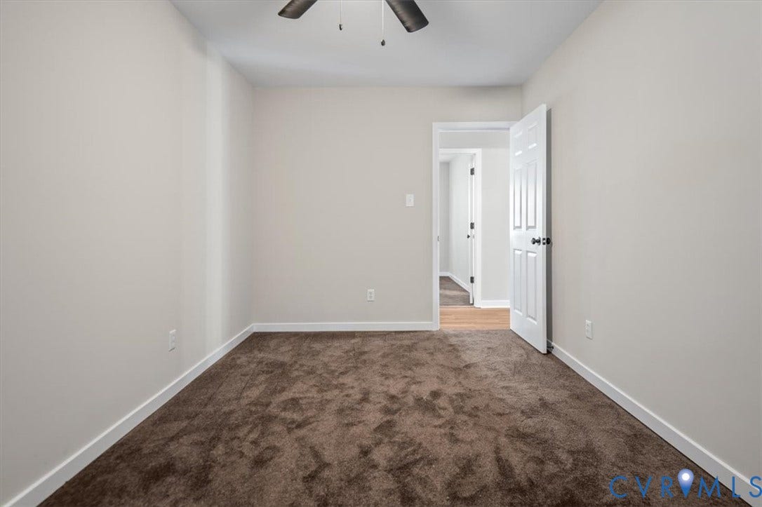 Brown carpet flooring, light neutral-toned walls, and a ceiling fan with light fixture