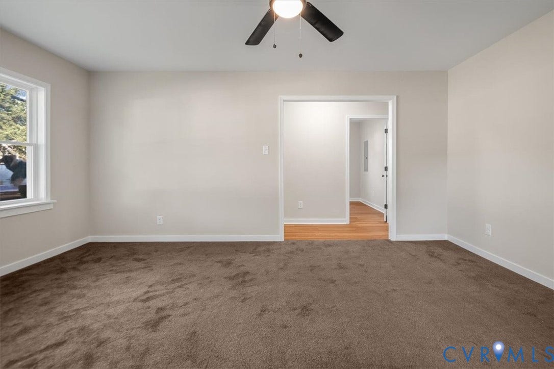 Neutral wall paint, brown carpeting, white trim, a ceiling fan, and a window with natural light