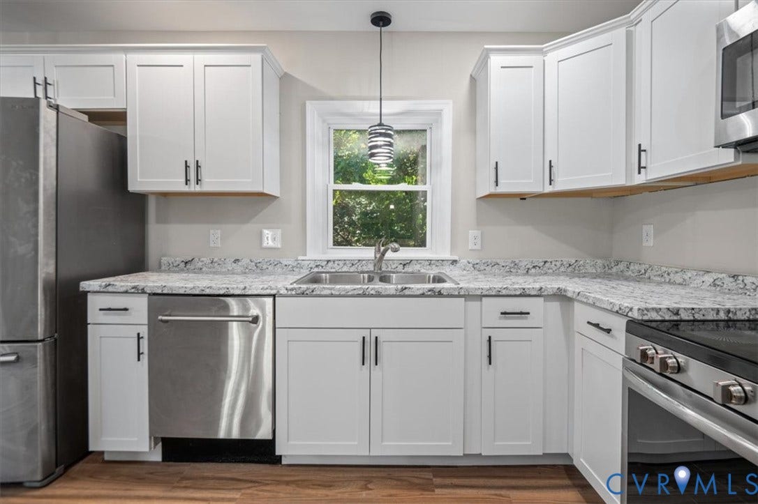 White shaker cabinetry, stone-finish countertops, stainless steel appliances, wood-finish flooring, and a contemporary pendant light fixture
