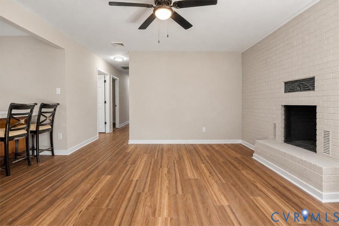 Wood-finish flooring throughout, complemented by a painted brick fireplace with a hearth