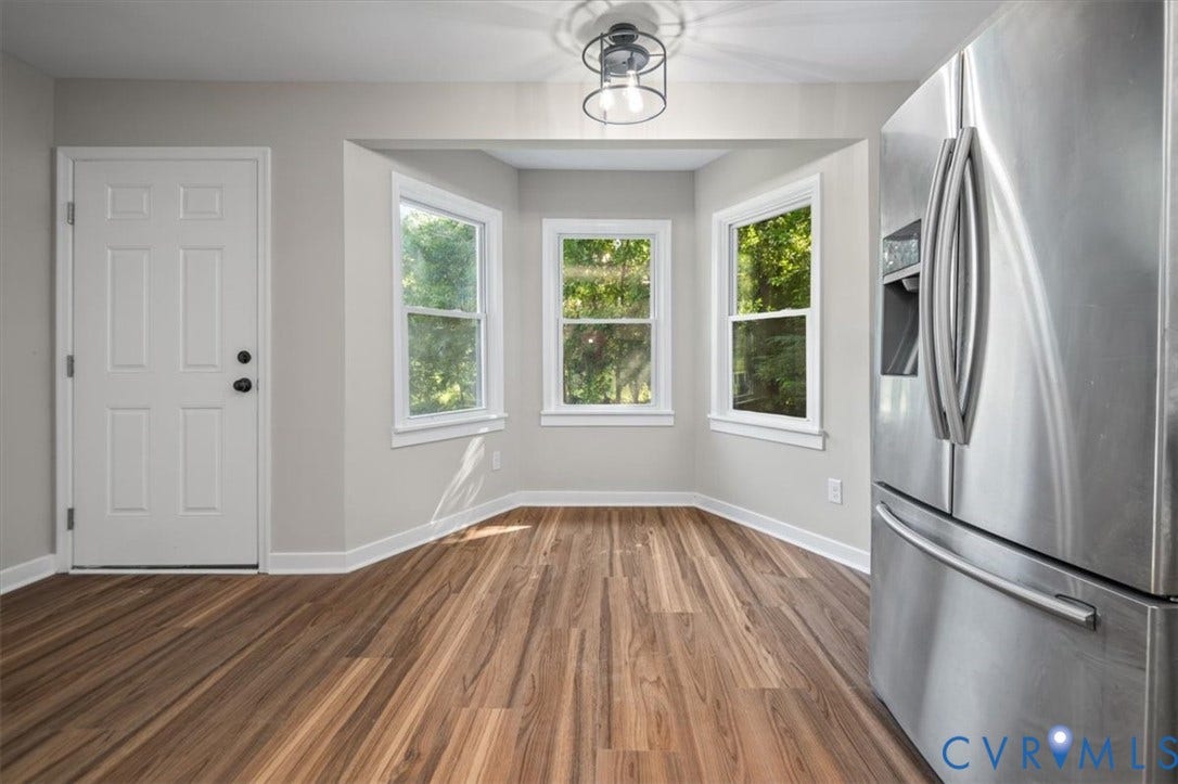 Wood-finish flooring, bay window, stainless steel refrigerator, paneled door, and recessed lighting