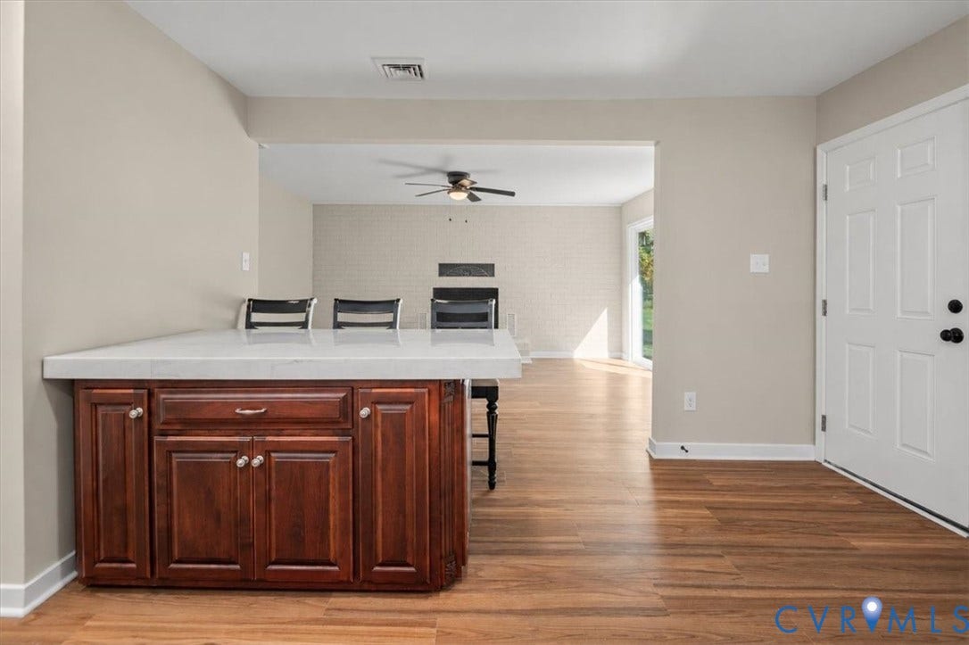Wood-finish flooring throughout, with a built-in island featuring wood cabinetry and a light-toned countertop