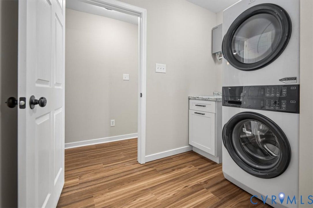 Laundry area featuring wood-finish flooring, white cabinetry, and light-toned walls