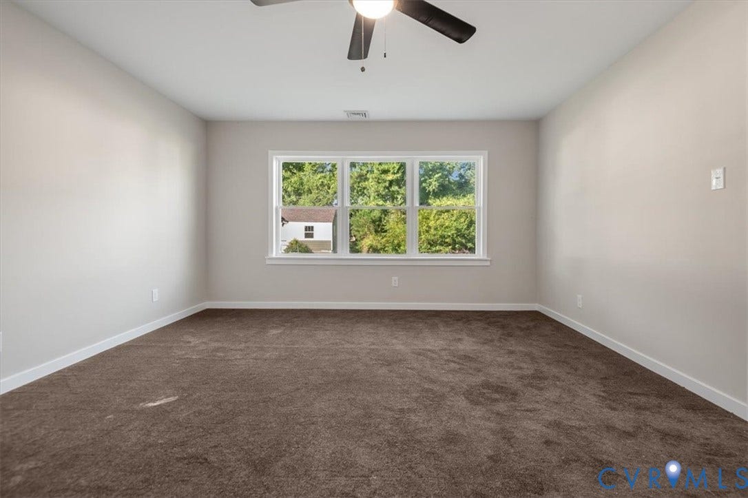 Recessed window, brown carpeting, white trim, light-toned walls, and a ceiling fan