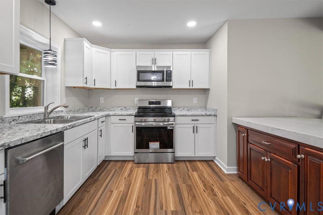 Kitchen featuring white shaker-style cabinetry, wood-finish flooring, stainless steel appliances, light-toned countertops, and recessed lighting