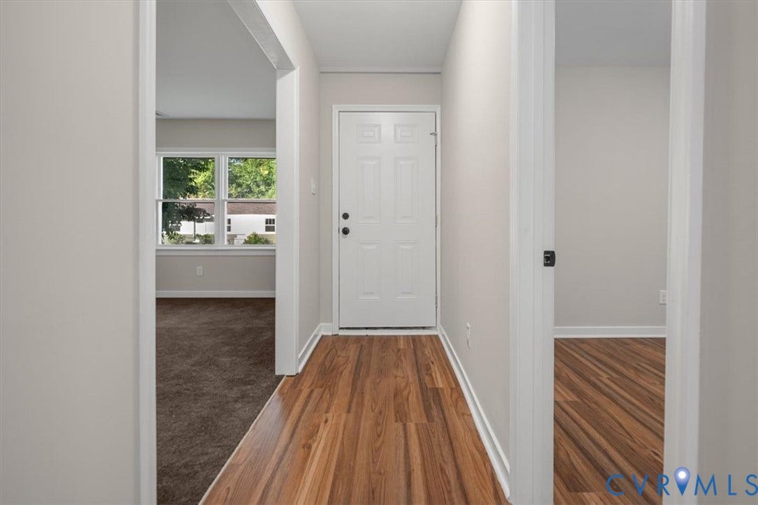 Entryway featuring wood-finish flooring, a white paneled door, and neutral wall tones