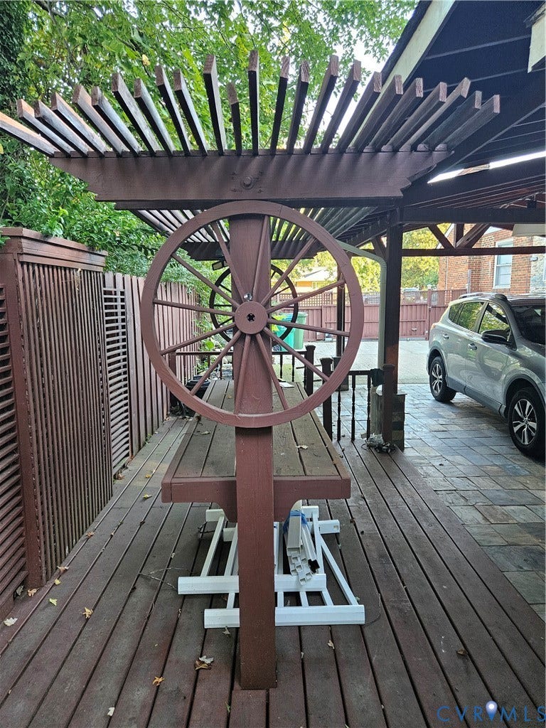 Wood deck with slatted privacy fencing, pergola, and wagon wheel accent