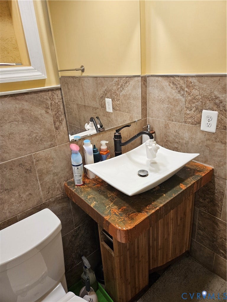Wall-mounted vanity with a vessel sink, dark bronze faucet, and tiled wainscoting