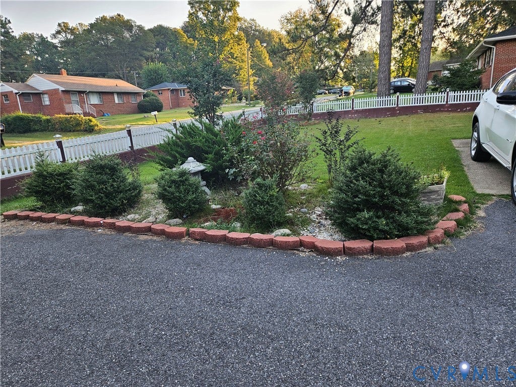 Landscaped front yard with mature shrubbery and a white picket fence