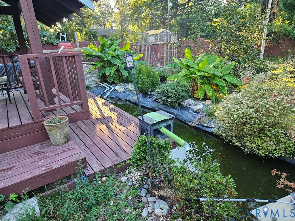 Wood-tone decking with railing, bordering a water feature with varied plantings