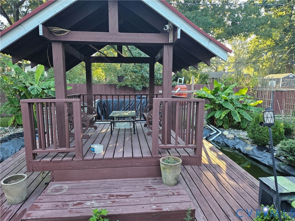 Wood deck with built-in gazebo, featuring a red roof and wood railing