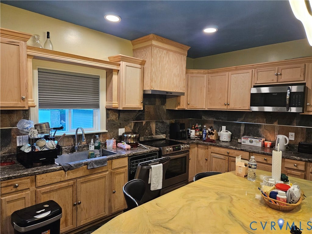 Kitchen featuring wood cabinetry, stainless steel appliances, stone backsplash, recessed lighting, and a large central island