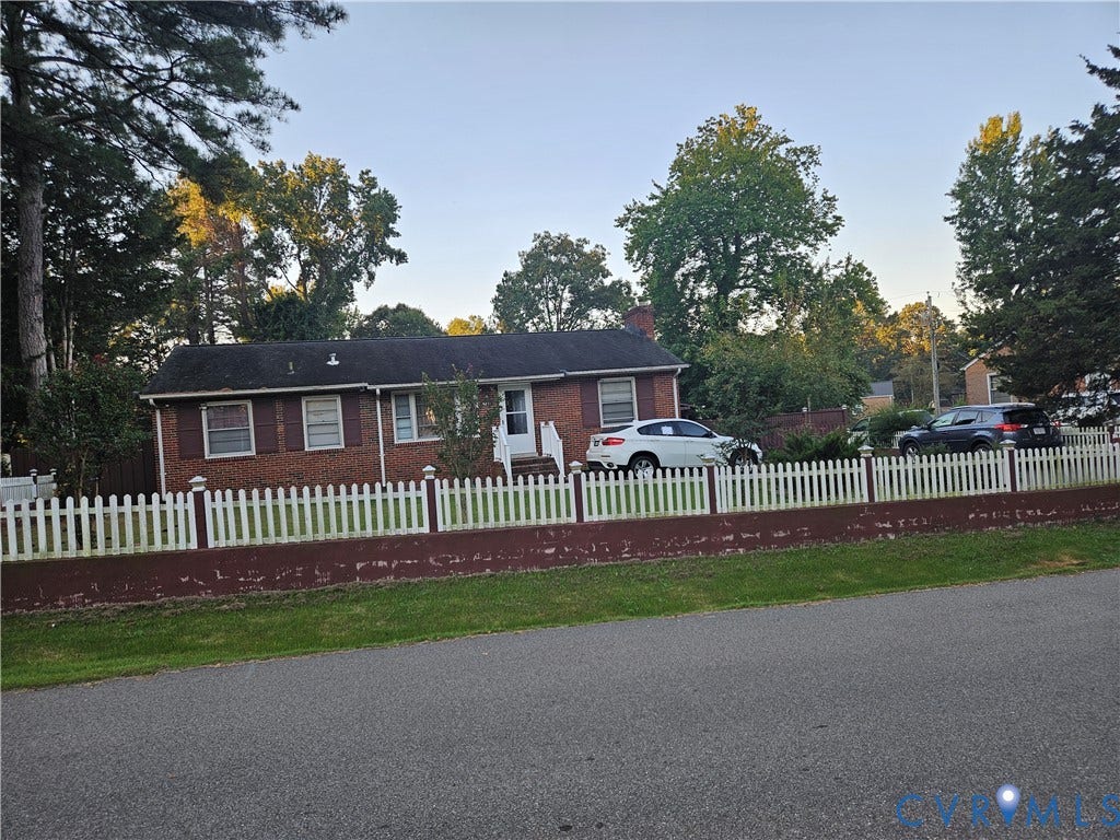 Brick exterior, white picket fence, mature trees, lawn area