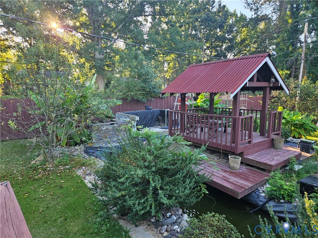 Outdoor gazebo with a corrugated red roof, integrated seating, and an adjacent water feature