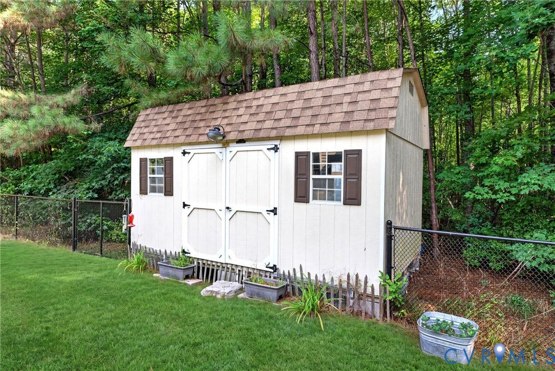 Storage shed featuring a shingle roof and double entry doors