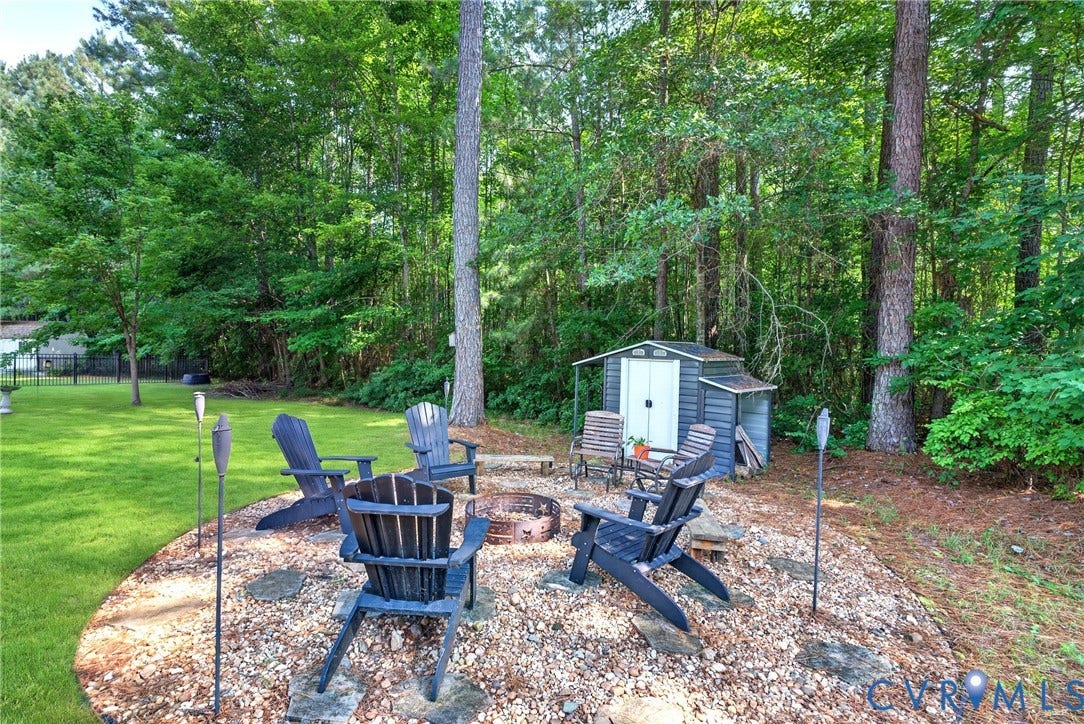 Fire pit area featuring a gravel base, stone accents, and shed for wood