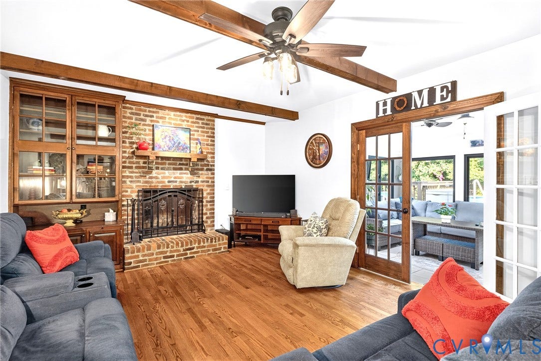 Hardwood Floors, Brick Fireplace with Shelf, Display Cabinet, Ceiling Fan, Wood Decorative Beams, Double French Doors leading to Sunroom