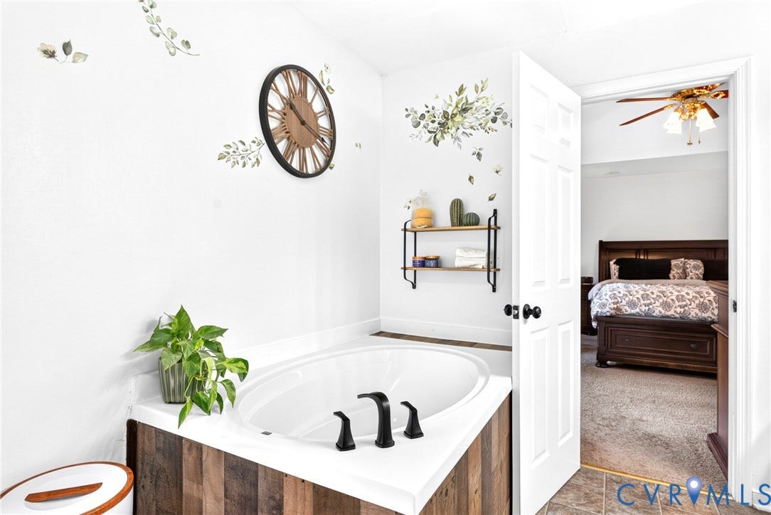 Soaking tub featuring a wood-finish surround and matte black fixtures