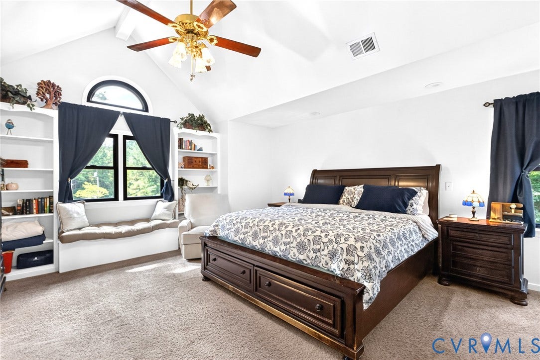 Bedroom featuring a vaulted ceiling with a ceiling fan, a window seat flanked by built-in shelving, and a prominent arched transom window