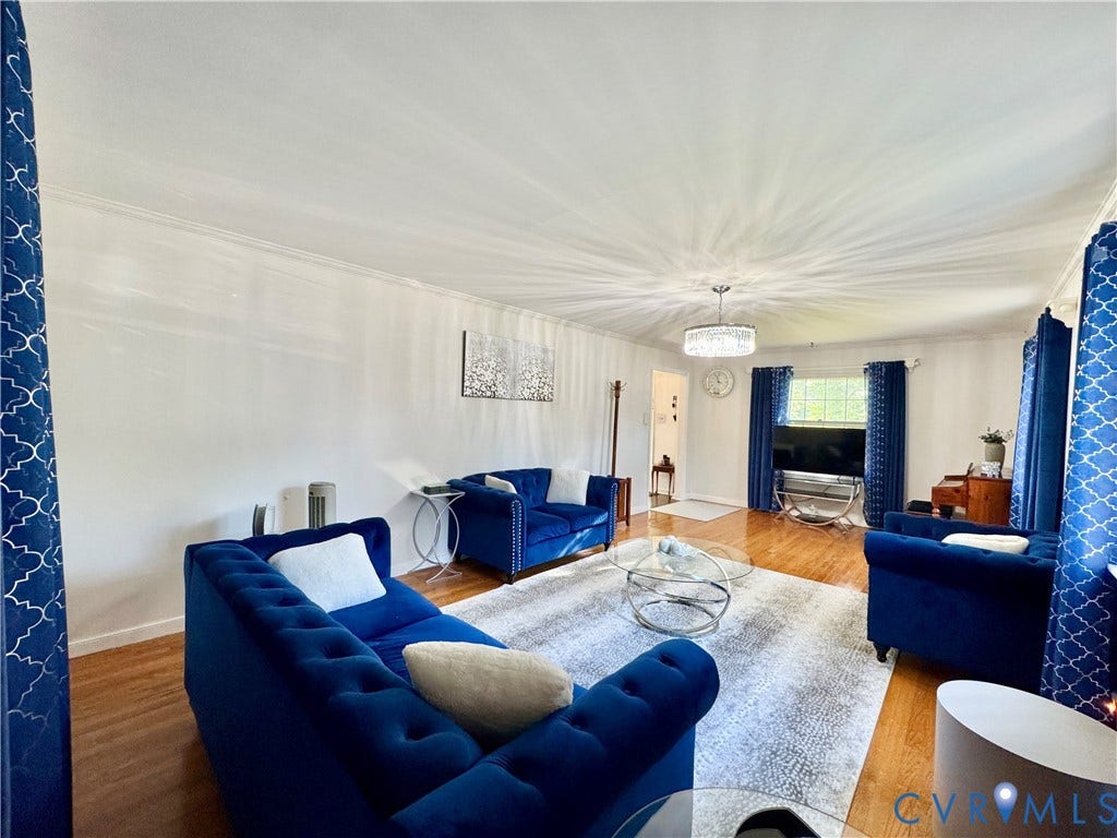 Hardwood flooring, crown molding, white walls, and a prominent chandelier