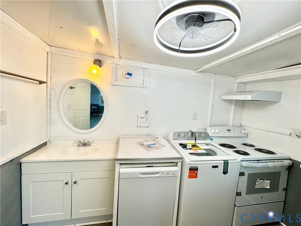 Integrated laundry appliances, built-in dishwasher, electric range with range hood, single-basin sink with vanity, and a ceiling fan with integrated lighting