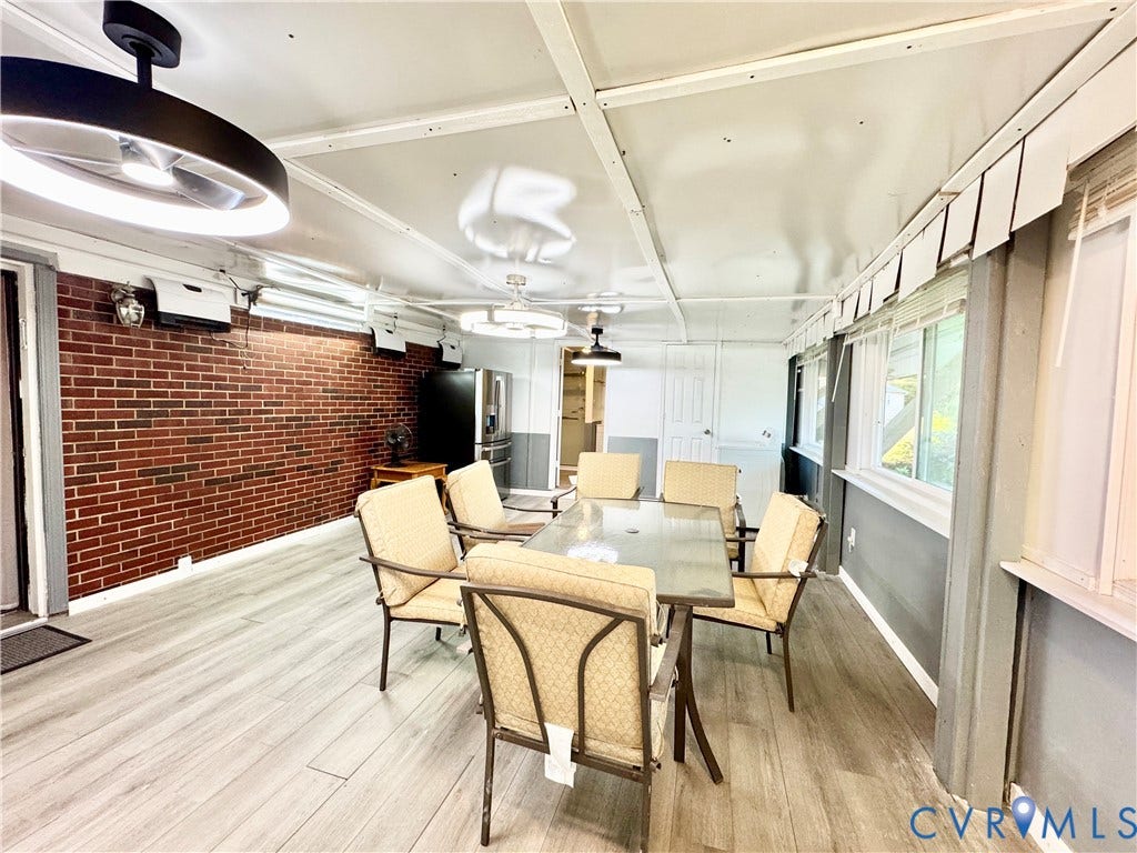 Red brick accent wall, light wood-finish flooring, multiple windows, and recessed lighting