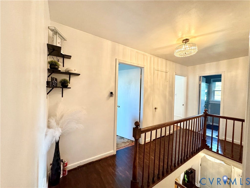 Wood-finish flooring, white walls, dark wood balusters, and a crystal semi-flush mount light fixture