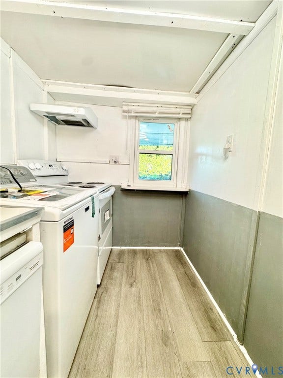 Kitchen with wood-finish flooring, white appliances, and a window for natural light