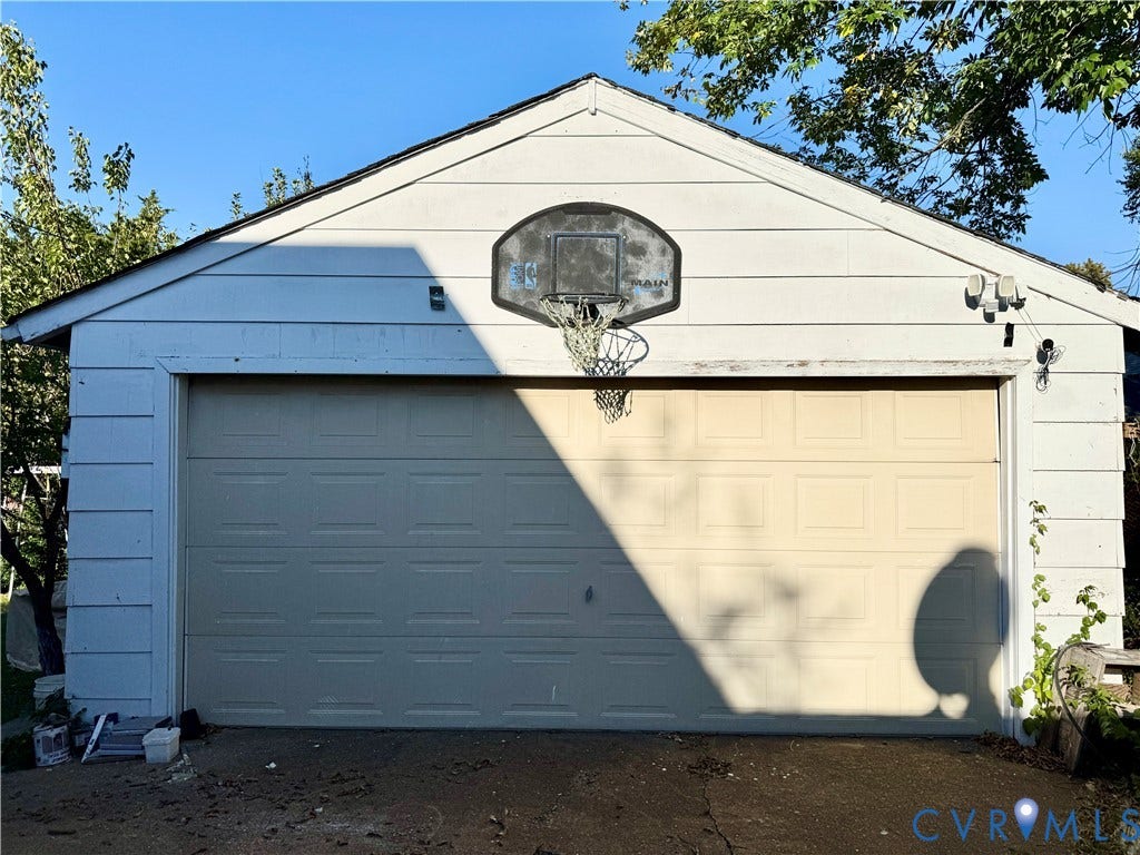 White siding exterior with a pitched roofline and an attached garage door