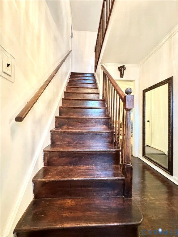 Staircase featuring wood treads, wood-finish railing, and a wood newel post