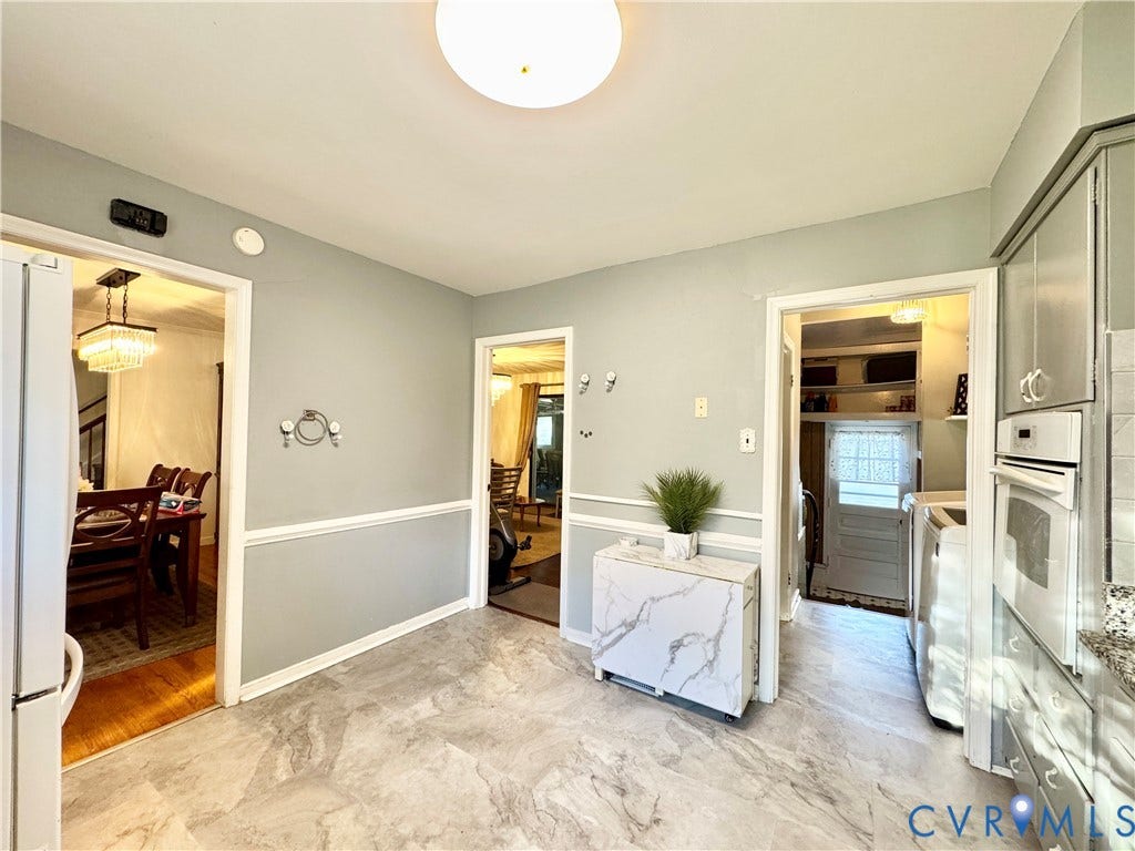 Light gray walls with white wainscoting, patterned flooring, and built-in wall oven and microwave