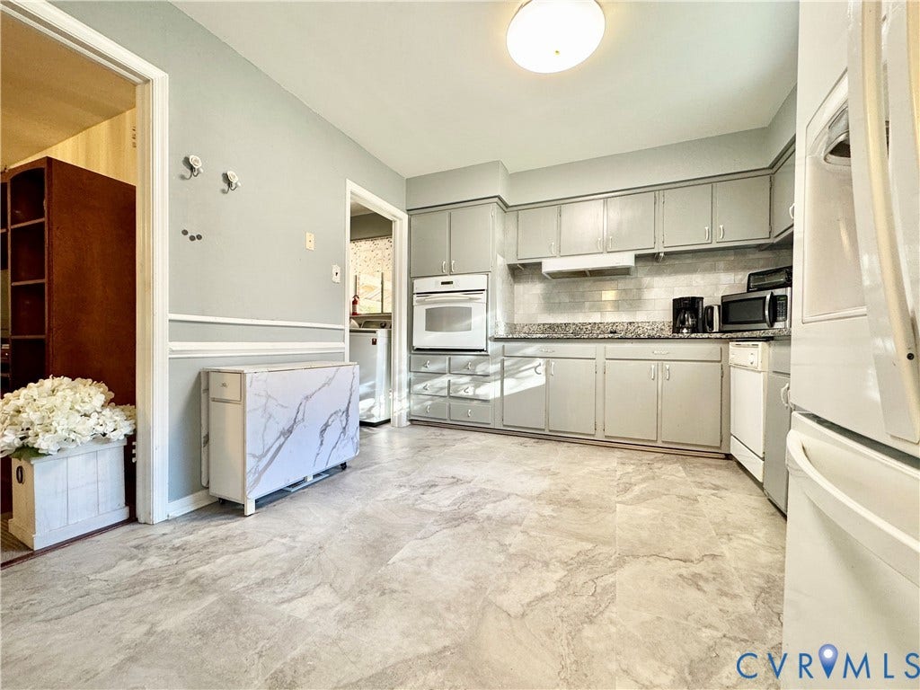 Kitchen featuring gray cabinetry, light-toned countertops, built-in wall oven, and a tiled backsplash