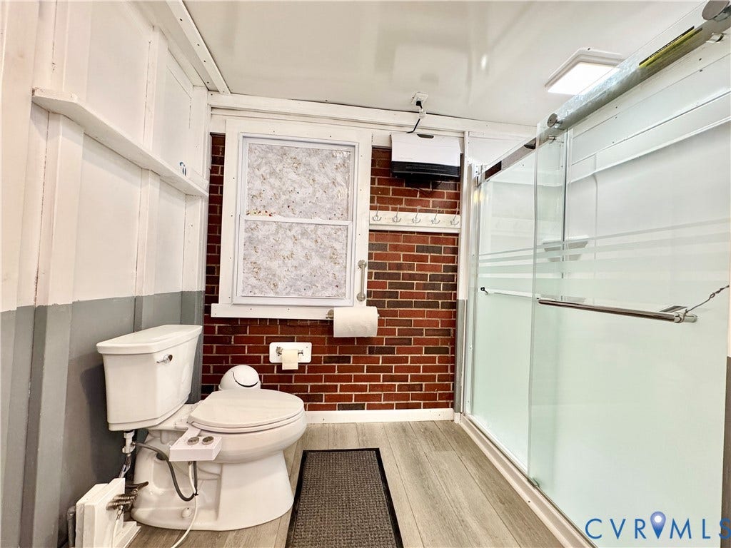 Wood-finish flooring with a glass-enclosed shower featuring a sliding door