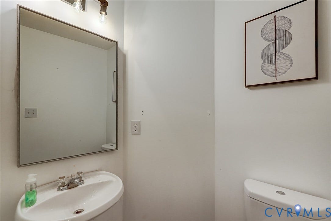 Wall-mounted sink with chrome-finish faucet, framed wall mirror, and modern lighting fixture
