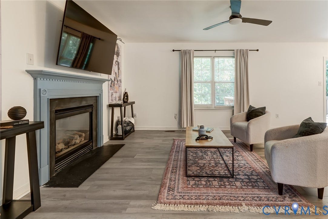 Gas fireplace with an ornate mantel, wood-finish flooring, and a ceiling fan