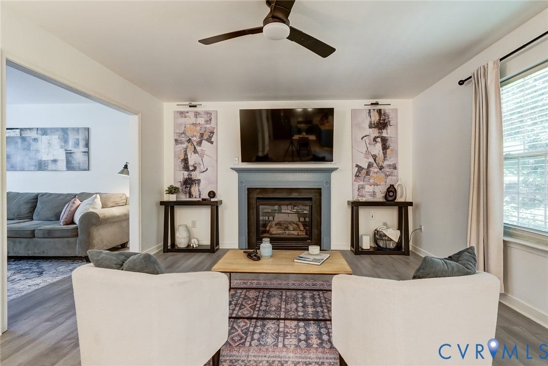 Living area with a fireplace, ceiling fan, and wood-finish flooring