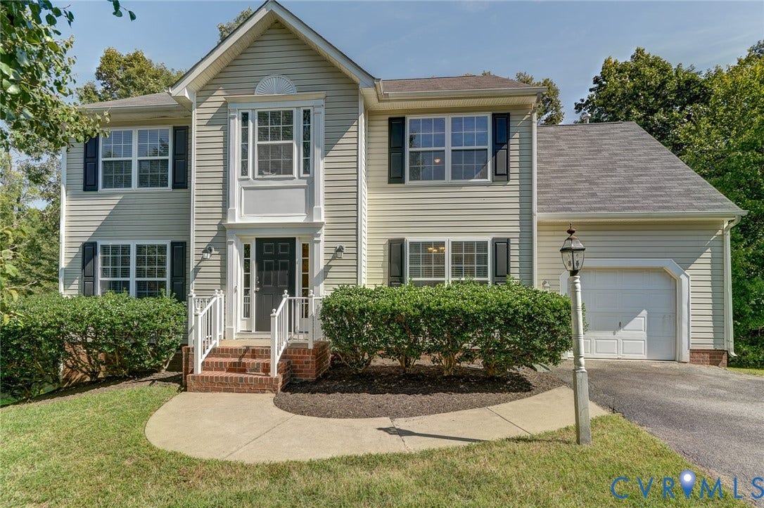 Two-story exterior with light-colored siding, black shutters, and an attached garage