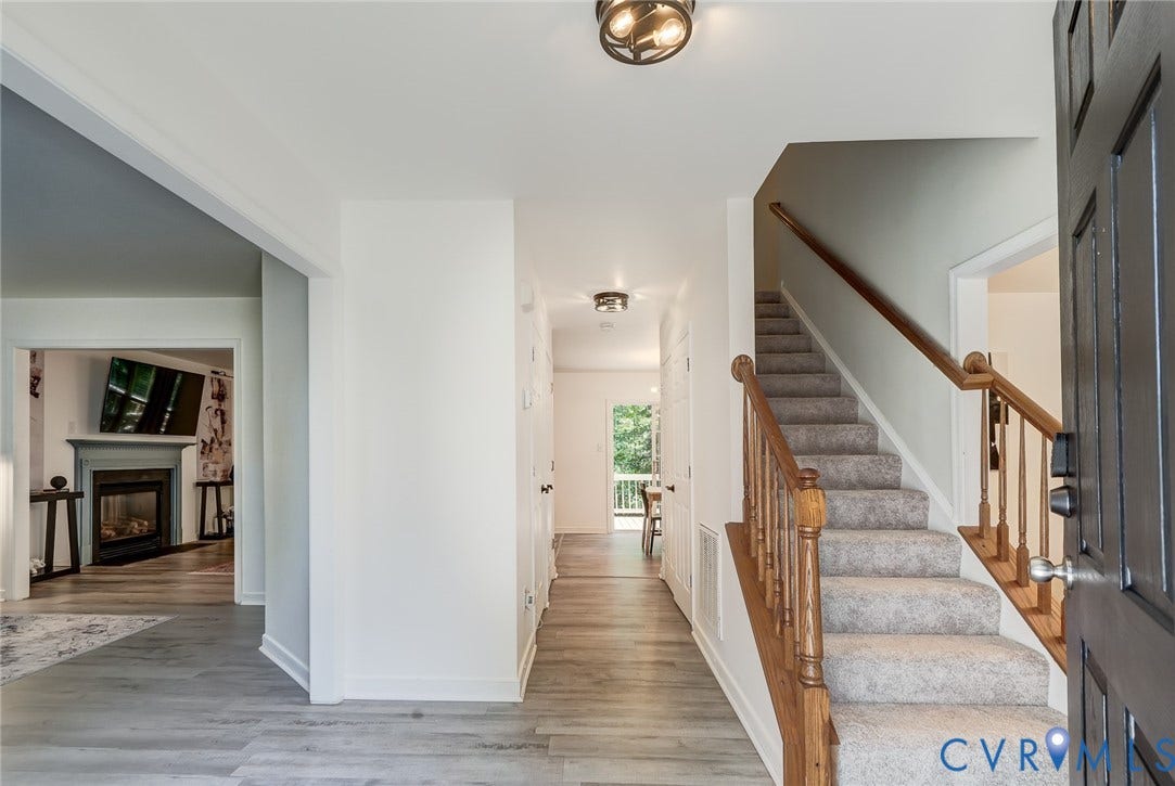 Entryway featuring wood-finish flooring, a carpeted staircase with wood banister, and a semi-flush mount ceiling light
