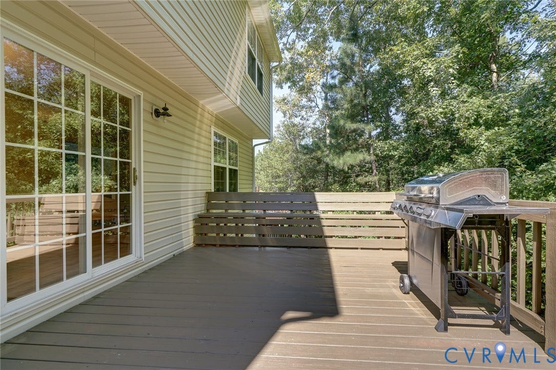 Exterior deck with horizontal slat railing, featuring a large sliding glass door with muntins, and a window with a white frame