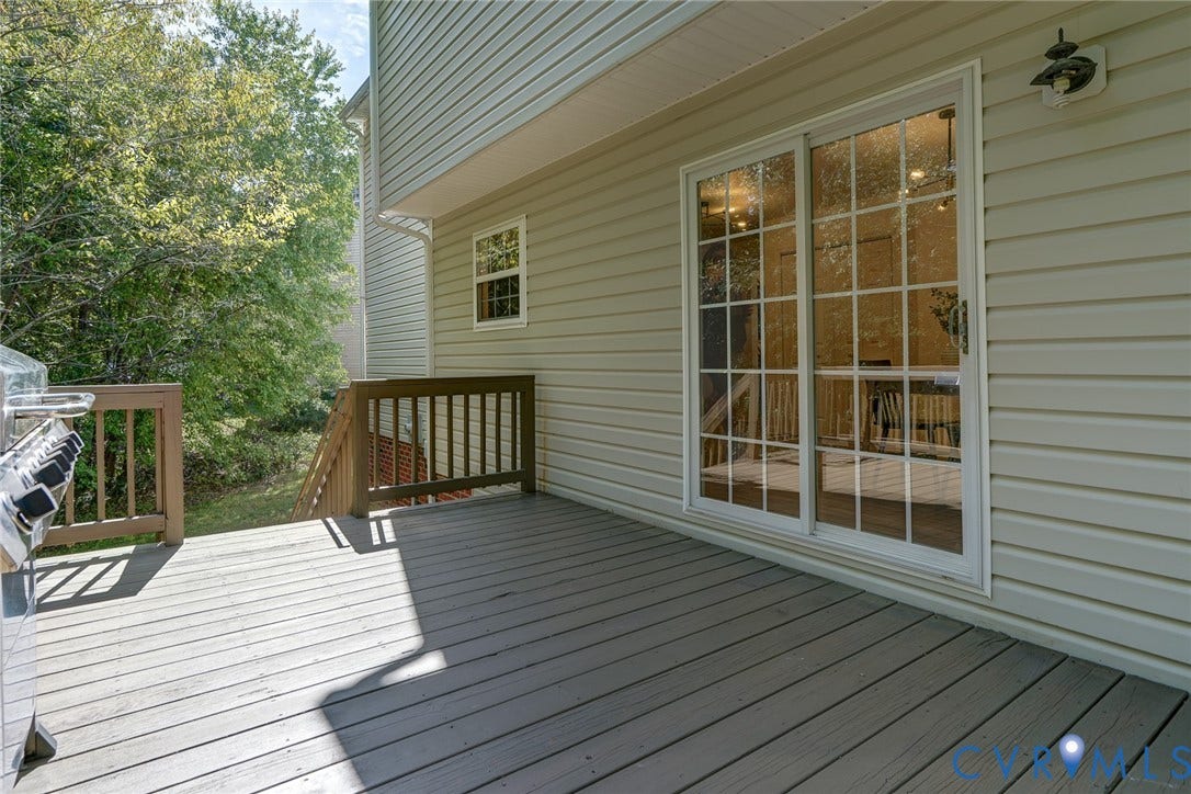Exterior deck featuring composite decking, wood railings, and a sliding glass door with grids
