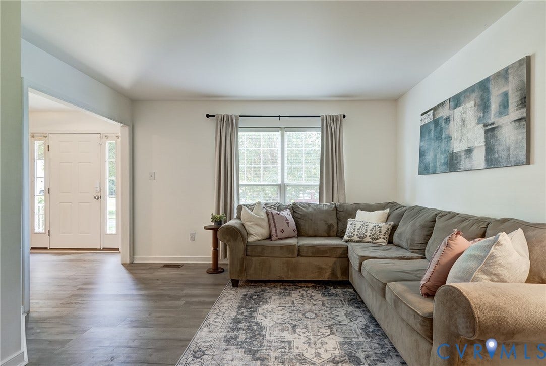 Recessed window with natural light, wood-finish flooring, white trim, neutral wall tones, and an arched entry