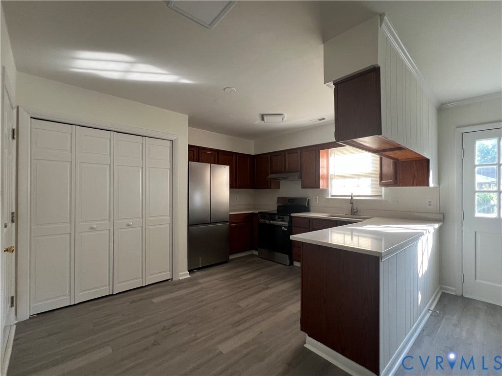 2112 Paramont Avenue, Collegue Park, Chesapeake, VA 23320 Kitchen featuring wood-finish flooring, dark wood cabinetry, light countertops, stainless steel refrigerator, and a built-in kitchen island with beadboard paneling